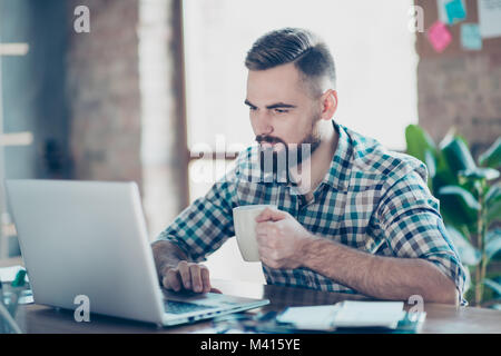 Concept of having a break at work. Concentrated calm peaceful serious office worker  watching carefully a video on the internet using his laptop and d Stock Photo