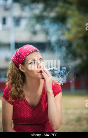 Red retro girl smoking in the park Stock Photo