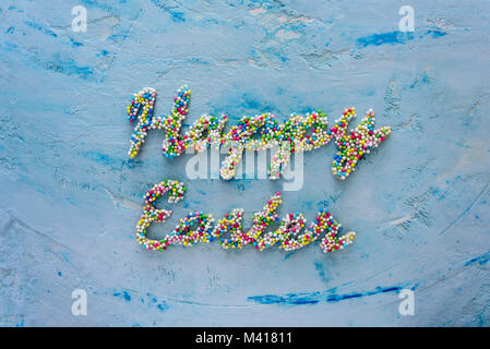 Words Happy Easter made of colorful candies on blue pastel background Stock Photo