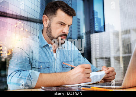Smart specialist looking at the screen of a laptop and frowning Stock Photo