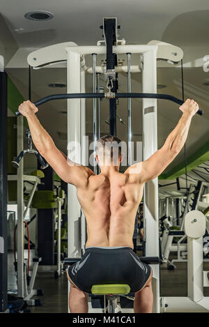 Shoulder pull down machine. Fitness man working out lat pulldown training at gym. Upper body strength exercise for the upper back. Stock Photo