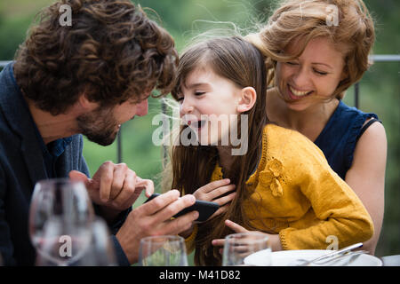 Family laughing with smartphone outdoors Stock Photo