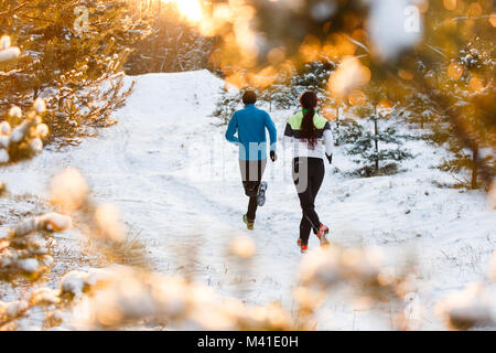 Image from back of running two athletes in winter park Stock Photo