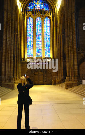 Woman Taking Photos of The Great West Window & the Tracey Emin's art work (I Feel You And I Know You Love Me) in Liverpool's Anglican Cathedral. Stock Photo