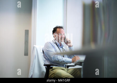 Male Medical Doctor on phone in his office Stock Photo