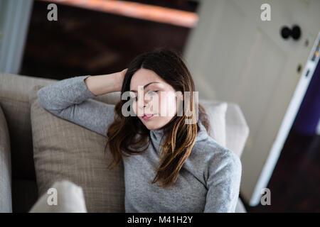 Young adult female relaxing on sofa at home Stock Photo