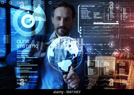 Smart programmer touching virtual planet while working with transparent screen Stock Photo