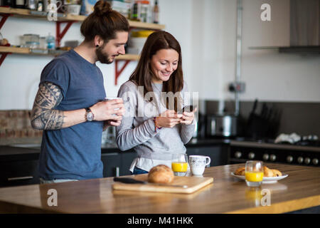 Young couple looking at smartphone together over breakfast Stock Photo