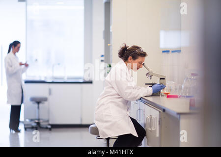 Female scientist looking through microscope Stock Photo