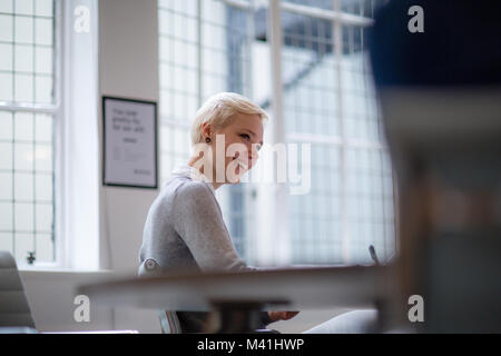 Young female businesswoman taking notes in meeting Stock Photo