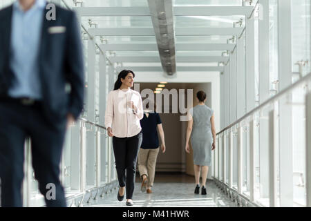 Female business executive walking through busy office corridor Stock Photo