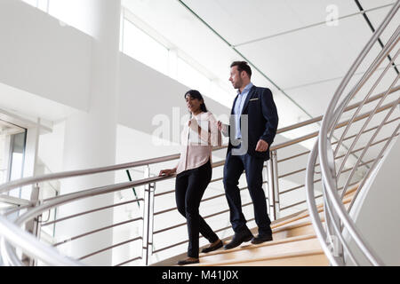 Business colleagues walking down spiral staircase Stock Photo
