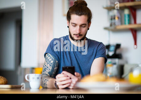 Young adult male having morning coffee and checking smartphone Stock Photo