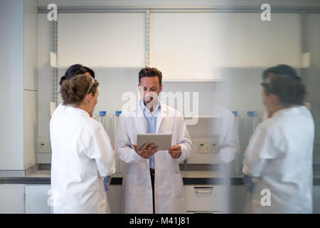 Team of scientists discussing experiment data on digital tablet Stock Photo