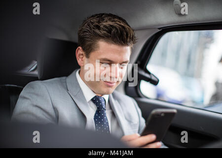 Businessman in taxi cab using smartphone Stock Photo