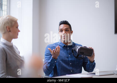 Designer presenting virtual reality headset in a meeting Stock Photo