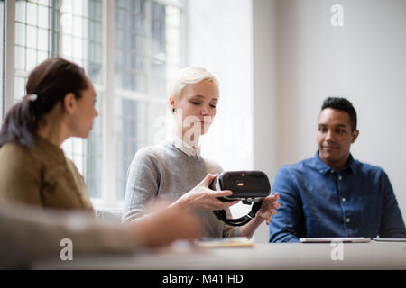 Designer presenting virtual reality headset in a meeting Stock Photo