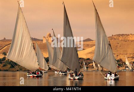 Egypt, Upper Egypt, Nubia, Nile Valley, Aswan, feluccas on Nile River transporting tourists towards the Aga Khan Mausoleum in the background Stock Photo