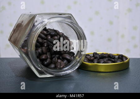 Coffee beans poured out off a jar with its cover. Stock Photo