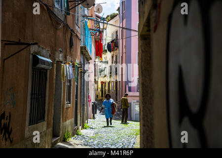A woman walks through an Alfama alleyway in Lisbon, Portugal. Stock Photo