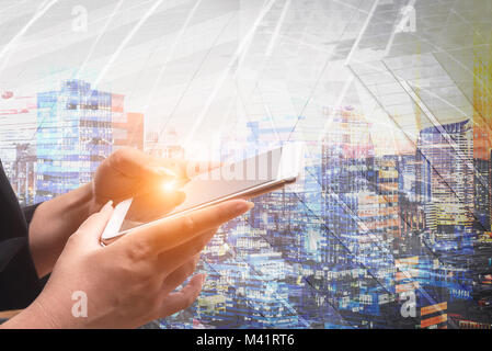 Businessman holding smart phone with wireless communication network icon and cityscape background. E-commerce smart connection business. internet of t Stock Photo