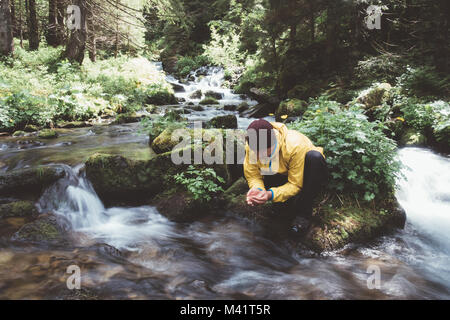 Man drink water from clear mountain stream Stock Photo