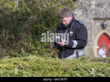 Traffic warden writing a parking ticket for an illegally parked car in England, UK. Parking penalty notice. Stock Photo