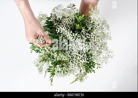 Buches of Flowers being arranged for a special occasion like valentines day. Woman trimming the stems of flowers after arranging them. Stock Photo