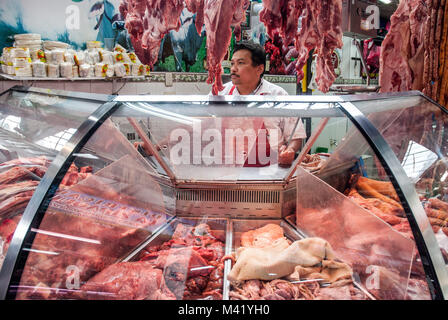 A butcher standing behind his meat counter holding a knife at a market in Bogota, Colombia Stock Photo