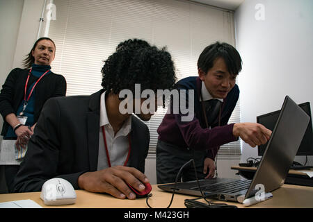 Kenzo Tanaka, right, an architectural engineer with Chuden Engineering Consultants (CEC), helps David Shoebrook, a Matthew C. Perry High School student from Marine Corps Air Station Iwakuni, Japan, while using an architectural computer program at CEC’s facility in Hiroshima, Feb. 8, 2018. The Defense Policy Review Initiative (DPRI) scheduled a day with CEC to host their first American visitors, which included five Matthew C. Perry High School students, DPRI employees and a Matthew C. Perry teacher, for a tour of the building and to visit with their employees to see how they work. (U.S. Marine  Stock Photo