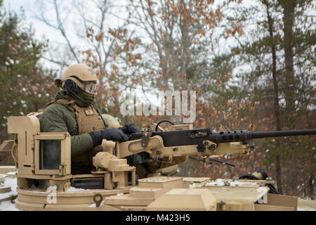 A Marine with Fox Company, 4th Tank Battalion, 4th Marine Division, looks forward from the gun turret of an Abrams M1A1 Main Battle Tank during exercise Winter Break 2018, near Camp Grayling, Michigan, Feb. 8, 2018. During training day two of Winter Break 18, Fox Co. Marines rehearsed formations, conducted advanced land navigation and terrain identification and performed preventative maintenance checks and services on their armored vehicles and equipment while increasing their operational capacity in single degree temperatures and snow covered terrain. Stock Photo