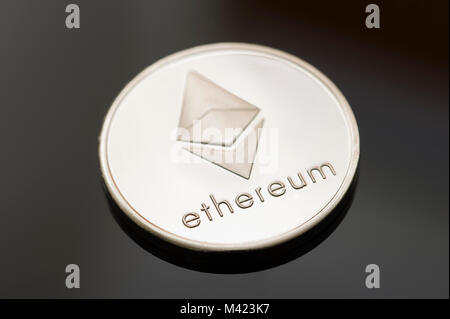 A single Ethereum (Ether) token or coin on a black background. One of many digital or cryptocurrencies that use blockchain technology Stock Photo