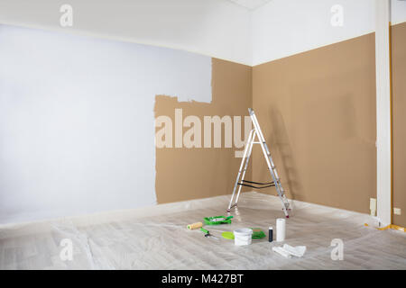 Half Painted White Wall With Ladder And Painting Equipments At Home Stock Photo