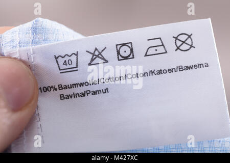 Close-up Of Person Reading Clothing Label Showing Washing Instructions Stock Photo