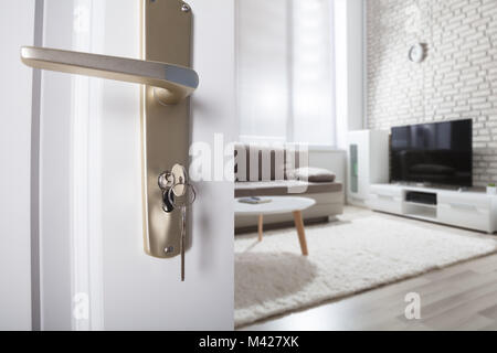 Close-up Of Door Handle With Inserted Key In The Keyhole And House Stock Photo