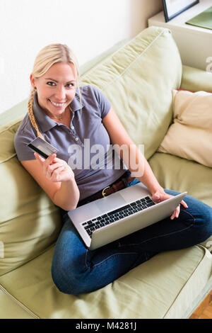 Relaxed young woman shopping online on laptop with the credit ca Stock Photo