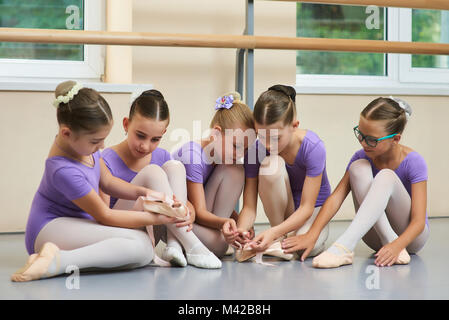 Young ballerinas at classical dance school. Young beautiful ballet dancers sitting on the floor. Kids having break. Stock Photo