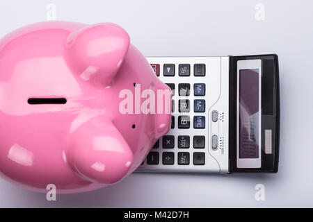 Elevated View Of Pink Piggy Bank And Calculator On White Background Stock Photo