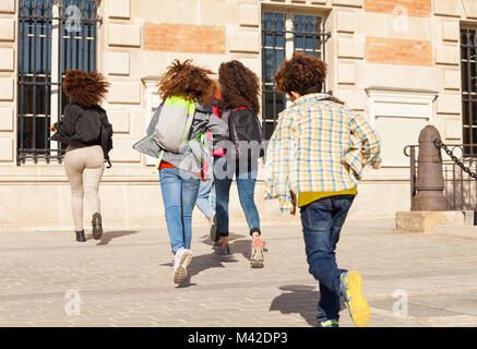 Big group of boys and girls with backpacks running to school at sunny day Stock Photo