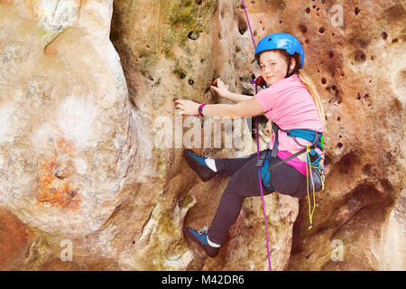 Teenage girl in helmet rock climbing on a very difficult route Stock Photo