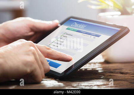 Close-up Of A Businessperson's Hand Filling Checklist Form On Digital Tablet Stock Photo