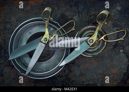Two old scissors lie on silver circles, diagonally along the frame, a flying pair of lovers, art still life for decorating the wall. Stock Photo