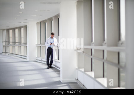 Male medical professional using smartphone in corridor Stock Photo