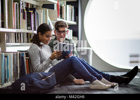 Students reading digital tablet in library Stock Photo