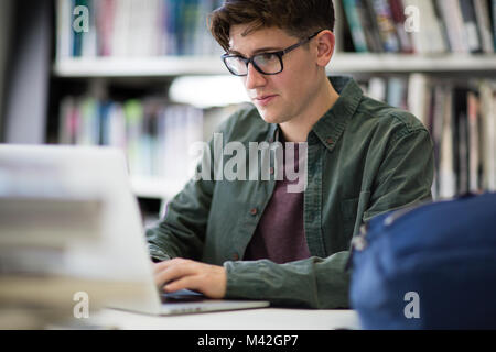 Student working on laptop in library Stock Photo
