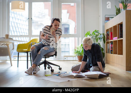 Colleagues discussing ideas with paperwork on office floor Stock Photo