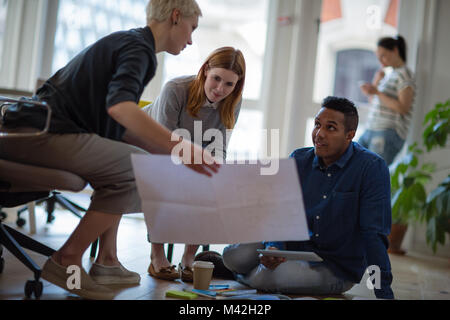 Colleagues looking at plans together in a meeting Stock Photo