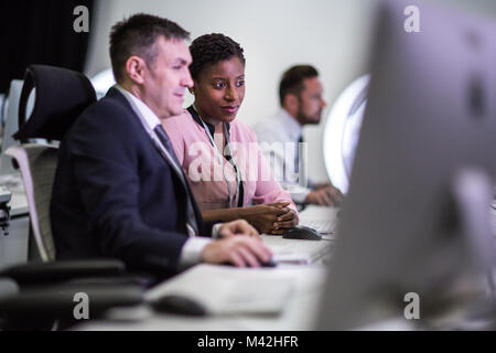 Colleagues in an office looking at a computer screen together Stock Photo