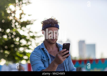 Young adult walking down street using smartphone Stock Photo