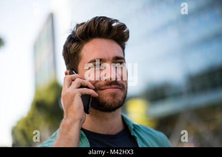 Young adult walking down street using smartphone Stock Photo